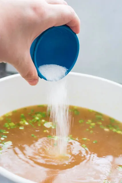 pouring sugar into wonton soup