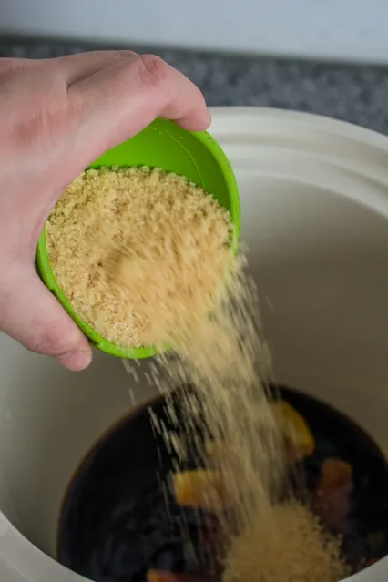 pouring brown sugar into crockpot for mongolian beef sauce