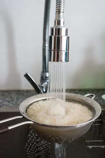 rinsing rice in a sieve for hainanese chicken rice