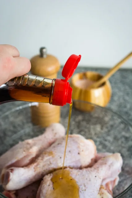 pouring sesame oil over chicken drumsticks