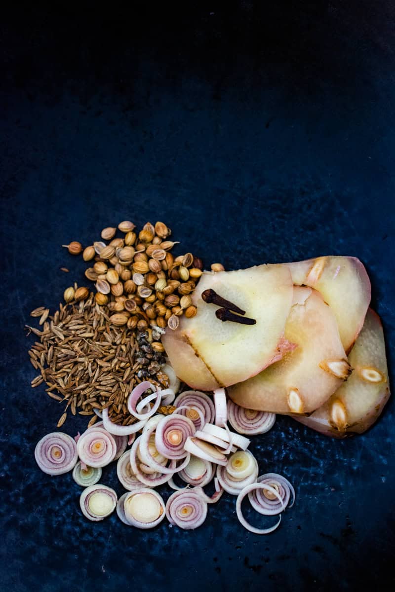 spices, sliced galangal, and sliced lemongrass in a wok