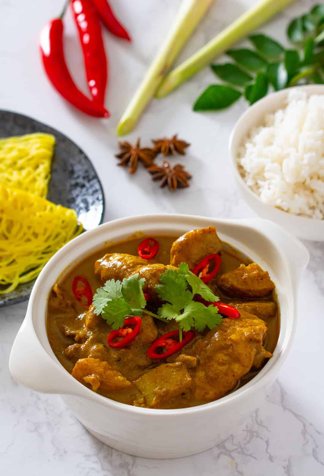 A bowl of Malaysian chicken curry (kari ayam) served with rice and roti jala