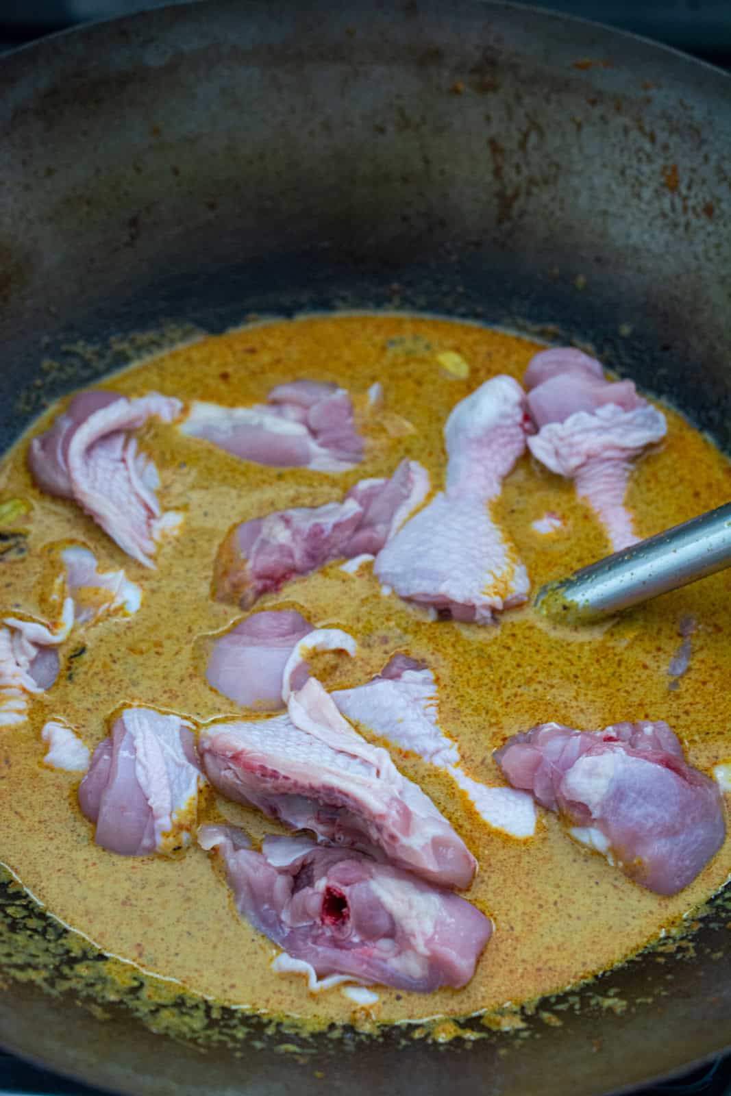 chicken pieces in chicken curry in a wok