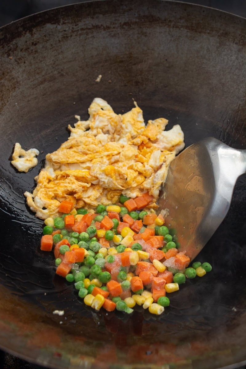frozen mixed vegetables in a wok, with scrambled eggs for spam fried rice