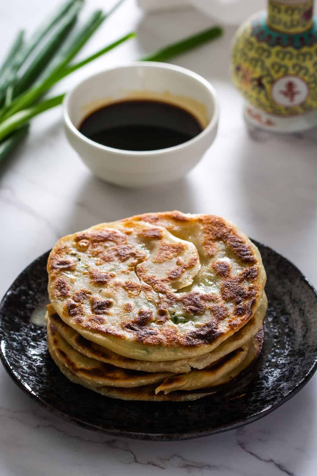 chinese scallion pancakes on black plate with dipping sauce