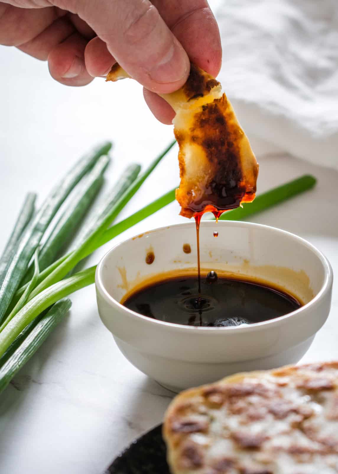 dipping chinese scallion pancake into sauce