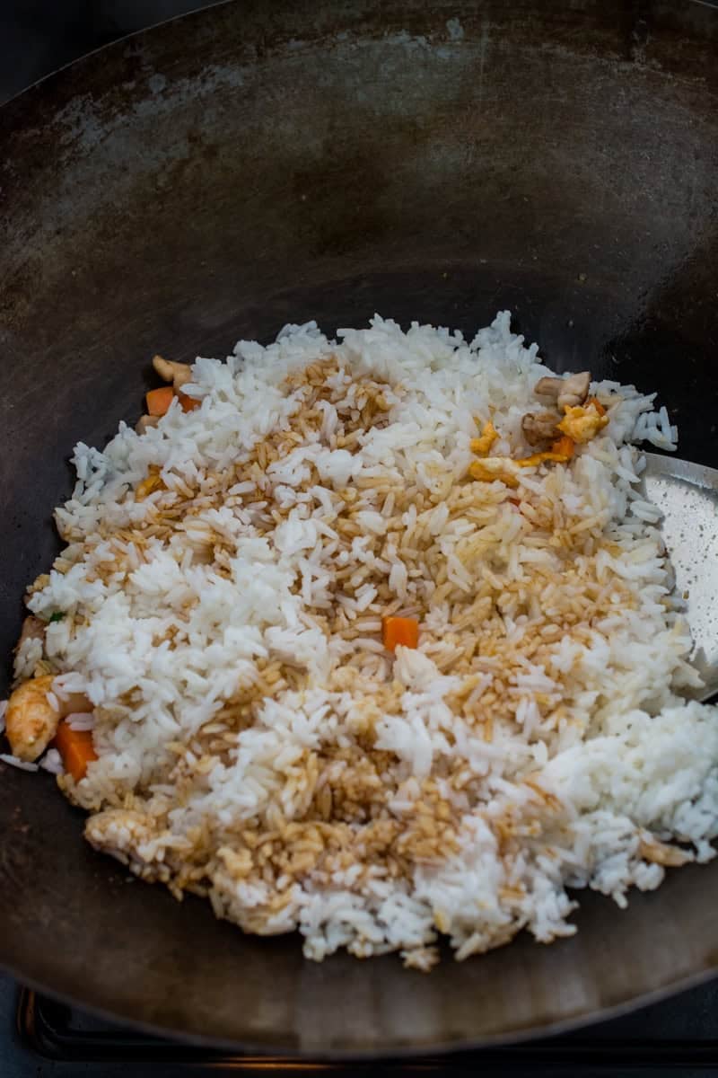 white rice in a wok with a drizzle of soy sauce