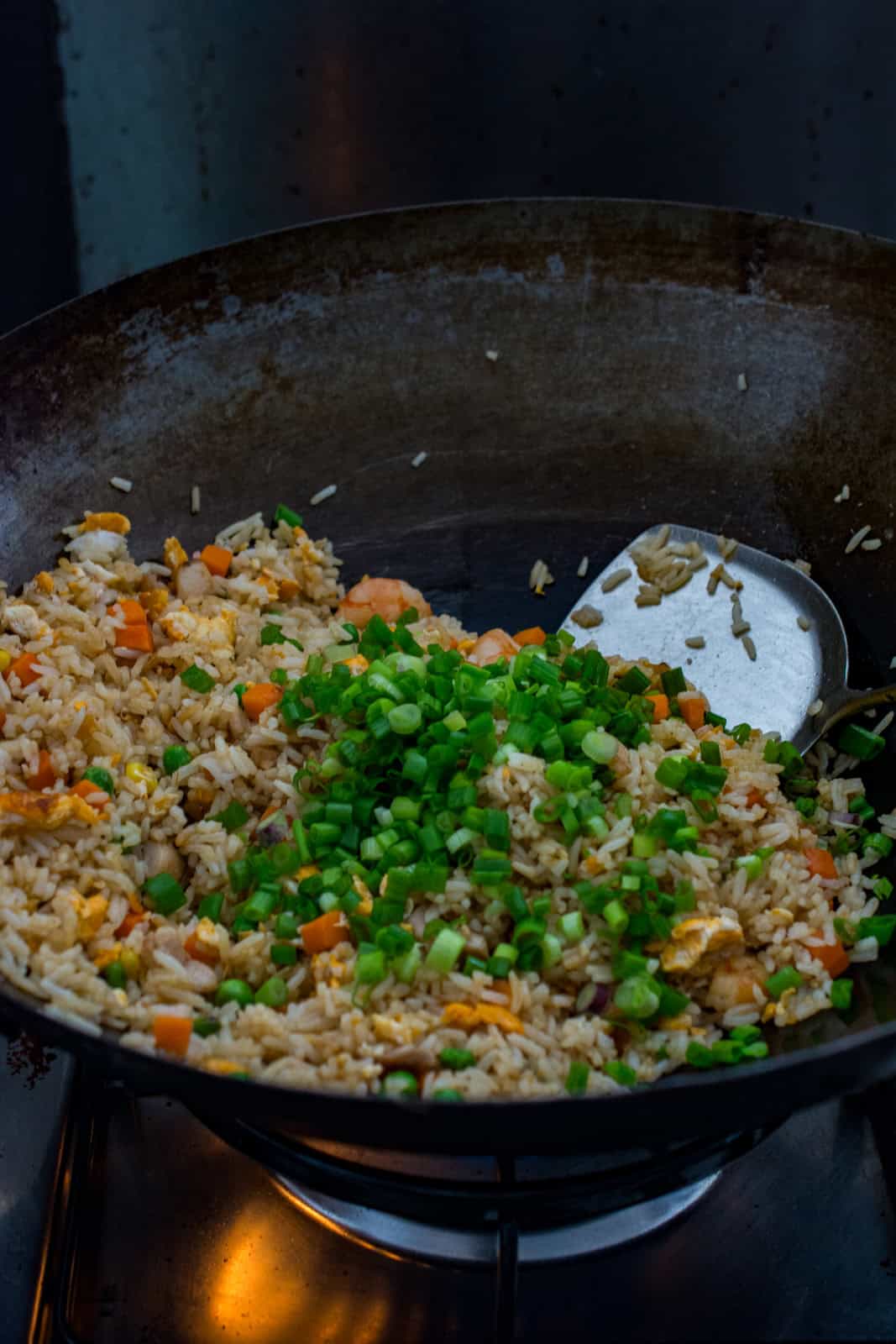 fried rice topped with scallions in a wok