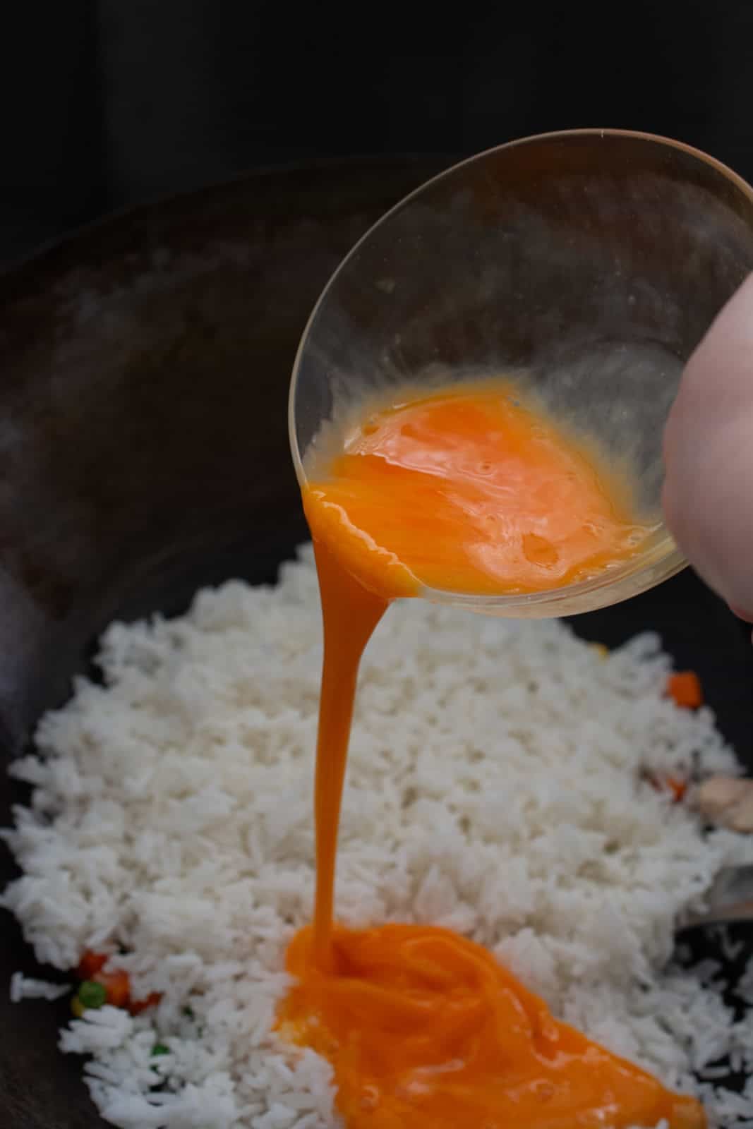 pouring egg over rice in a wok